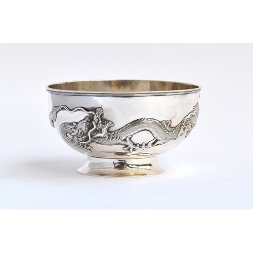 89 - A Chinese silver rose bowl, encircled by two chased dragons in relief, on a circular spreading foot,... 