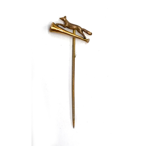 77 - A 9ct gold tie pin depicting running fox above hunting horn