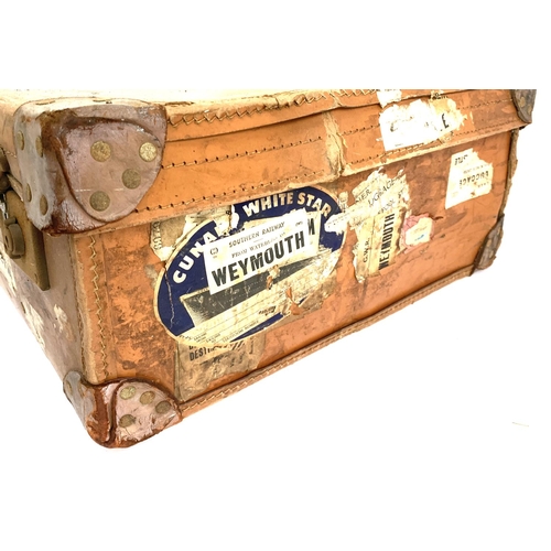 1065 - A vintage suitcase, with leather corner fittings, various travel stickers including Weymouth, Cunard... 