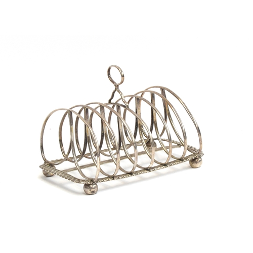 79 - A silver six division toast rack, on gadrooned border and four ball feet, marks unclear, 16cm long, ... 