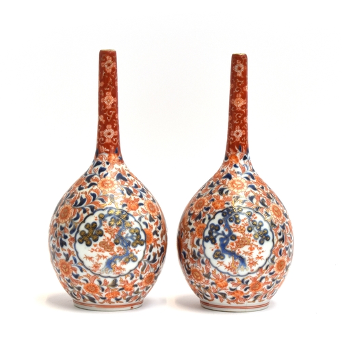 222 - A pair of Japanese imari bottle vases, decorated with interlocking florals surrounding a central loz... 