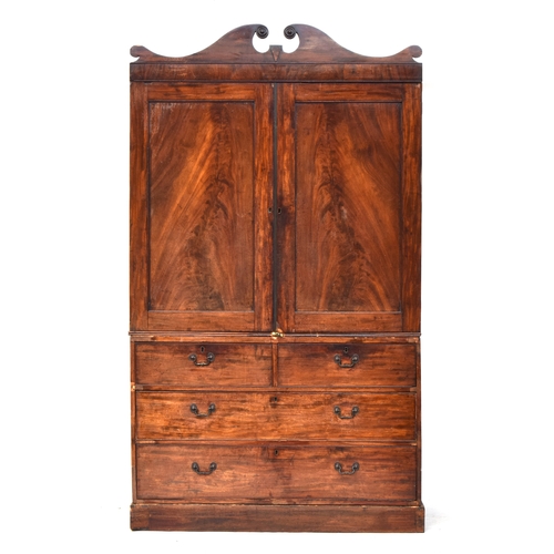 544 - A 19th century mahogany linen press, the broken pediment over two panelled doors opening to slides, ... 