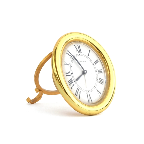 50 - A Cartier desk clock, the oval gold plated desk clock with quartz movement, white dial with Roman nu... 