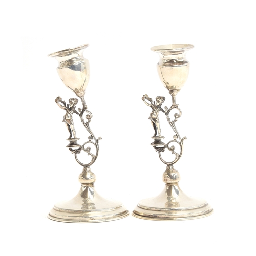 151 - A pair of 925 silver candlesticks, each with cherub and scrollwork stem, on spreading circular foot,... 