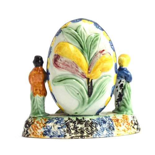 235 - An unusual Staffordshire Prattware moneybox, decorated with figures and a dog beside an oval contain... 