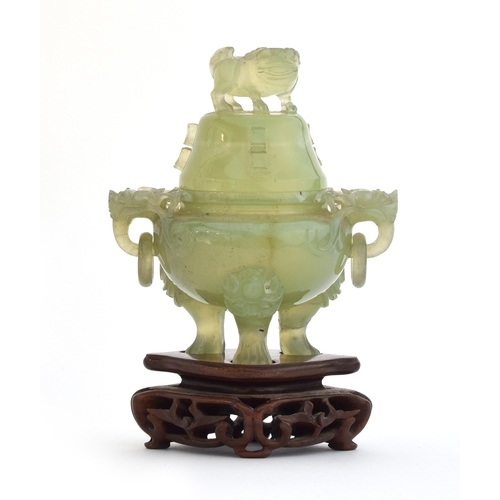 204 - A Chinese carved jade lidded censer on a carved hardwood stand, with foo dog finial, dragon masks an... 