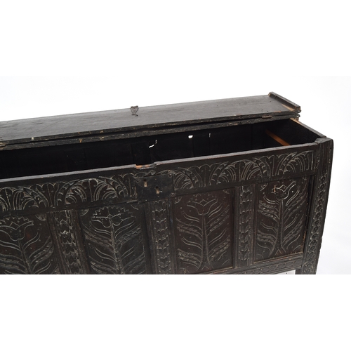 583 - An early 18th century four panel oak coffer, two plank bifold top over a demilune frieze and floral ... 