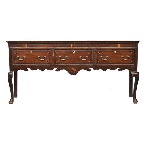 589 - A George II oak dresser base, moulded top over three inlaid and crossbanded drawers, shaped apron, a... 