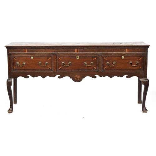 589 - A George II oak dresser base, moulded top over three inlaid and crossbanded drawers, shaped apron, a... 