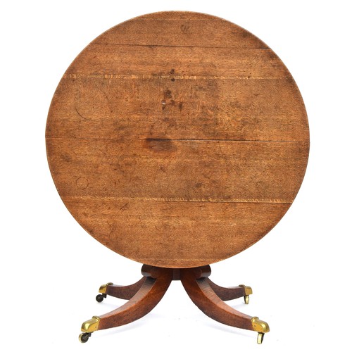 647 - A Regency oak circular tip-top dining table, c.1820, the hinged top on a turned column with hipped s... 