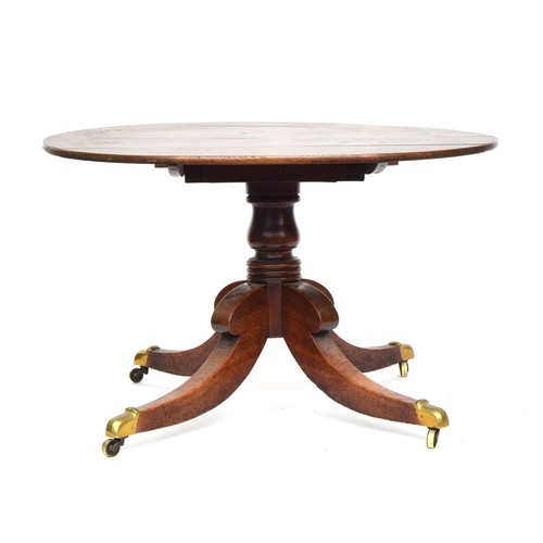 647 - A Regency oak circular tip-top dining table, c.1820, the hinged top on a turned column with hipped s... 