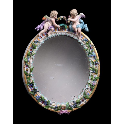 266 - A Meissen flower encrusted and gilt metal mounted oval strut looking glass, surmounted with putti, l... 