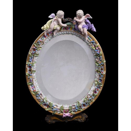 267 - A Meissen flower encrusted and gilt metal mounted oval strut looking glass, surmounted with putti, l... 