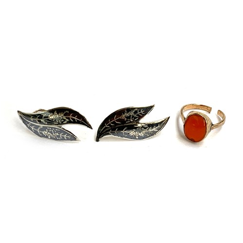 31 - A yellow metal ring set with a carnelian cabochon (af); together with a pair of Siam silver niello s... 