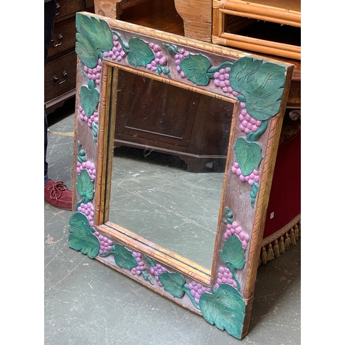 929 - A carved wall mirror, the frame carved and painted with grape and vine decoration, 85x76cm