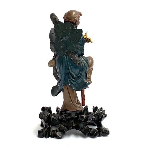 404 - A Chinese carved polychrome wood figure of an ascetic monk, modelled holding a gilt bird, on a pierc... 