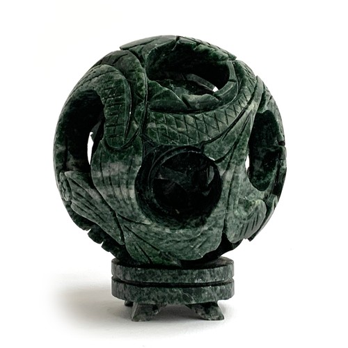 320 - A Chinese 'jade' puzzle ball with small plinth stand, 9cmD