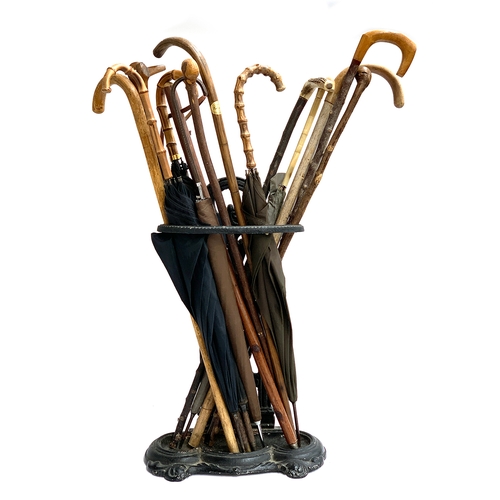 48 - A cast iron stick stand containing a quantity of various walking sticks and vintage umbrellas