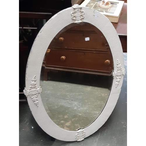 917 - An oval wall mirror with bevelled glass and white painted metal frame, 92x67cm