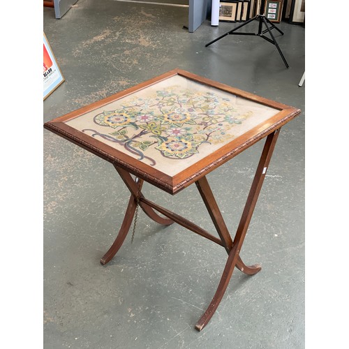 932 - A converting oak framed occasional table/fire screen, with glazed embroidered panel with floral deco... 