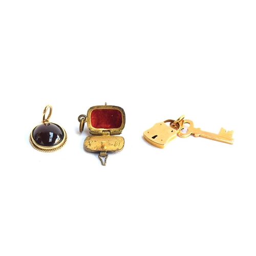 26 - A 14ct gold pendant set with a garnet cabochon, 1.4cm long; together with a yellow metal padlock and... 