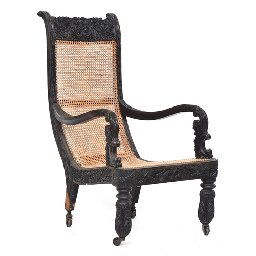 711 - An Anglo-Indian ebony open arm library chair, c.1840, with fully caned back and seat, the frame prof... 