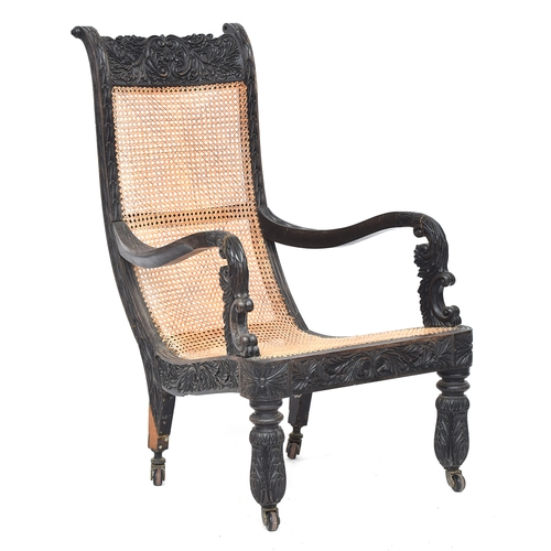 711 - An Anglo-Indian ebony open arm library chair, c.1840, with fully caned back and seat, the frame prof... 