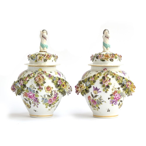 239 - A pair of floral encrusted lidded urns, hand painted with encrusted swags, each lid with kneeling pu... 