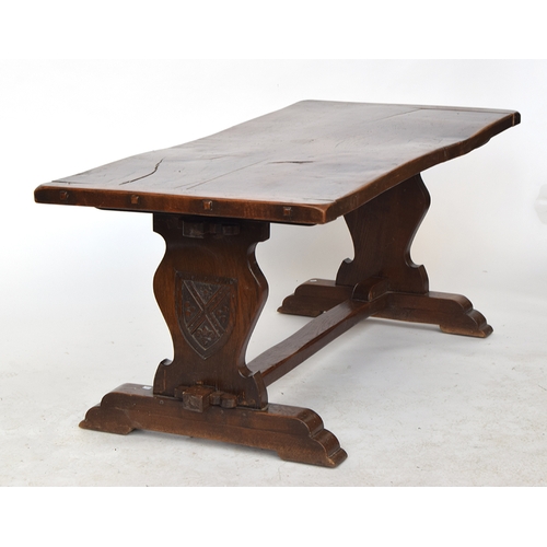 564 - An oak refectory table, two plank cleated top, each support with carved shield motif, 181cm wide, 83... 