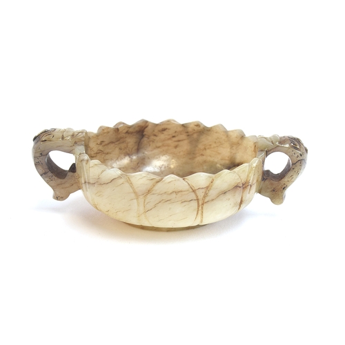 177 - A Chinese mutton fat and mottled grey jade twin handled cup, of shallow lotus form with twin dragon ... 