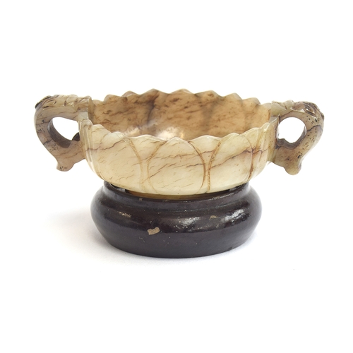 177 - A Chinese mutton fat and mottled grey jade twin handled cup, of shallow lotus form with twin dragon ... 