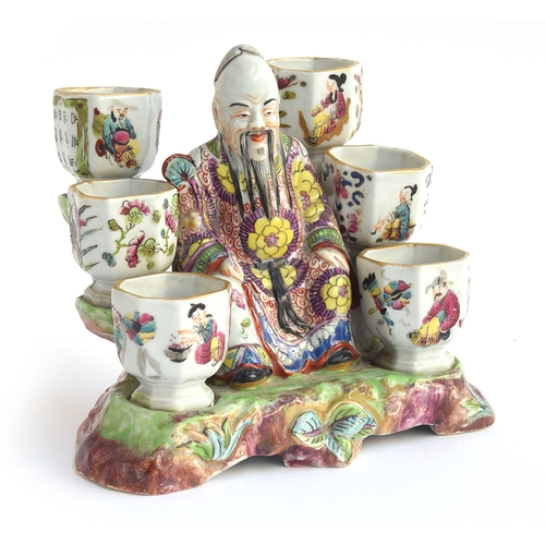 186 - A 19th century porcelain chinoiserie figural inkwell in the form of a seated sage surrounded by six ... 