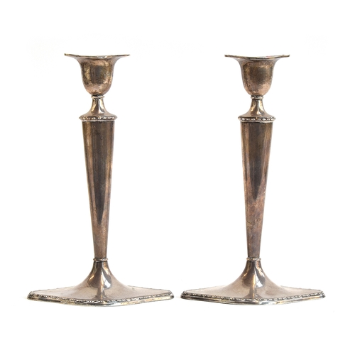 137 - A pair of loaded silver candlesticks by William Hutton & Sons Ltd, Sheffield 1913, on slender oval t... 