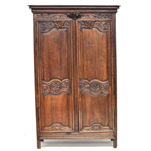 558 - An 18th century French armoire, the pediment top with floral urn carving below, two carved and panel... 