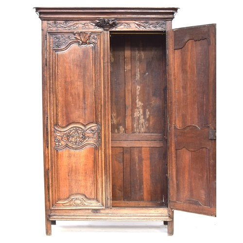 558 - An 18th century French armoire, the pediment top with floral urn carving below, two carved and panel... 