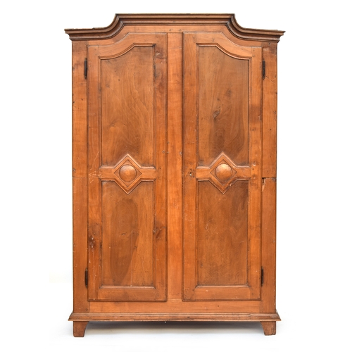 559 - A Continental fruitwood armoire, moulded pediment top over two panelled doors, the carcass cut in tw... 