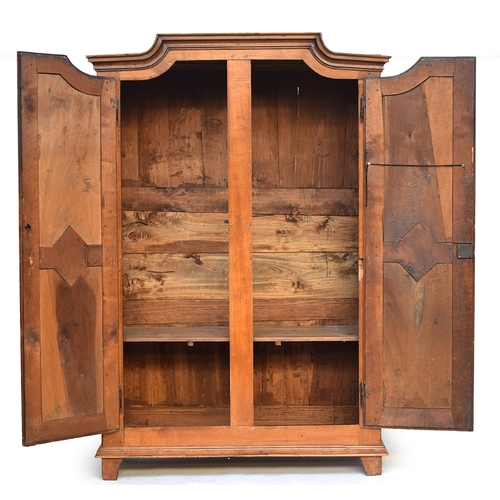 559 - A Continental fruitwood armoire, moulded pediment top over two panelled doors, the carcass cut in tw... 