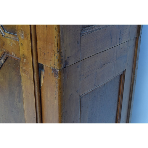 559 - A Continental fruitwood armoire, moulded pediment top over two panelled doors, the carcass cut in tw... 