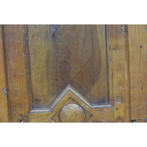 559 - A Continental fruitwood armoire, moulded pediment top over two panelled doors, the carcass cut in tw... 