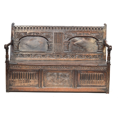 562 - A 17th century oak hall bench or settle, c.1650, carved and inlaid back over a hinged seat, either e... 