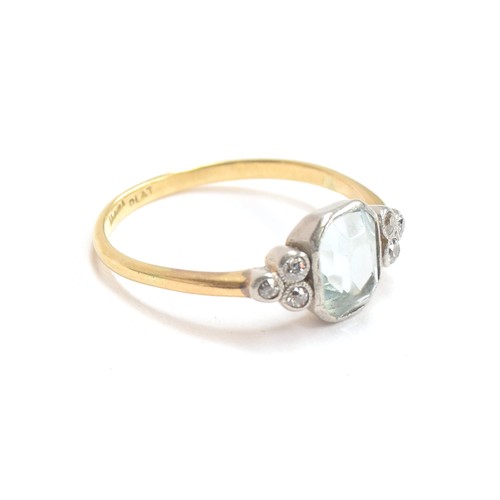 35A - An 18ct gold and platinum ring set with a large emerald cut aquamarine between two trefoils of old c... 