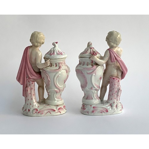 215A - A pair of Schierholz porcelain figures of putti holding an encrusted posy of flowers beside a lidded... 