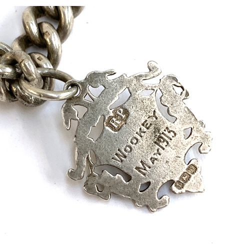 44 - A heavy silver curb link fob chain with dog clip and a badge inscribed Wookey May 1913, each link in... 