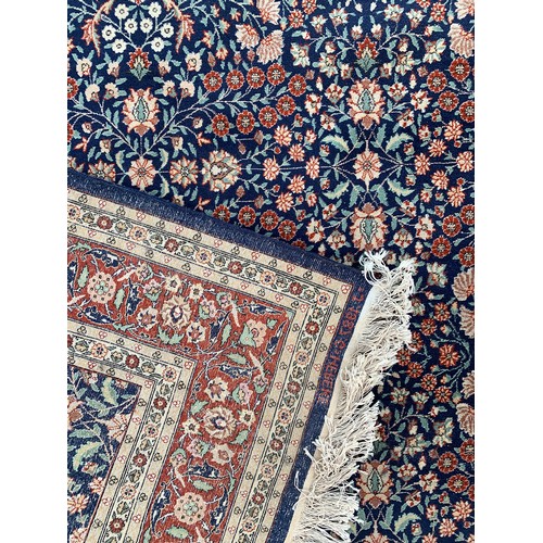 745 - A very large Turkish rug, marked 'J. 1987. G = HEREKE', blue ground with floral design, 620x343