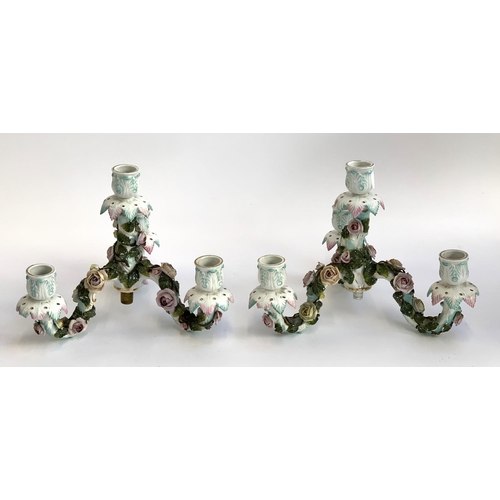 69 - A pair of porcelain floral encrusted three arm candlestick holders (af), 20cmH