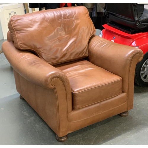 845 - A brown leather armchair with outward scrolling arms, on turned wooden feet, 92cmW