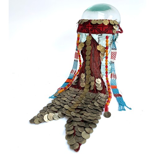 169A - A Palestinian bridal wedding headdress and burqa veil, the woven cap mounted with coins from the Ott... 