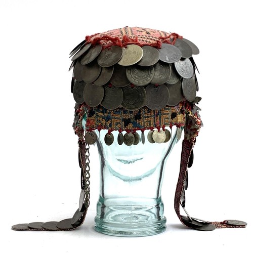 169A - A Palestinian bridal wedding headdress and burqa veil, the woven cap mounted with coins from the Ott... 