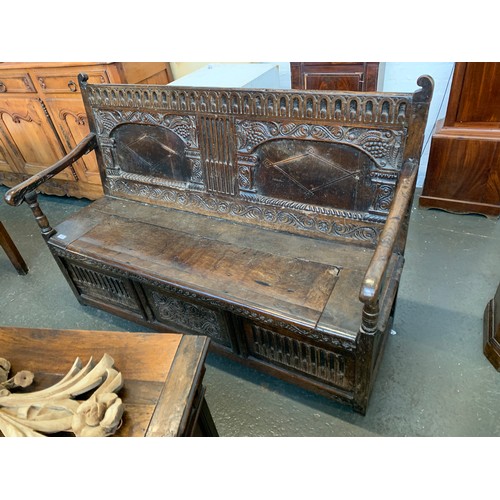 562 - A 17th century oak hall bench or settle, c.1650, carved and inlaid back over a hinged seat, either e... 