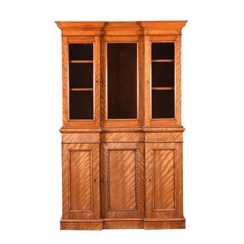 516 - A Victorian satin birch bookcase cabinet, the lower panel moulded doors opening to shelved interiors... 